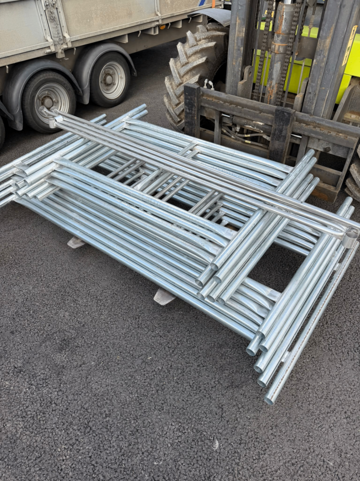 Scaffolding tower sections stacked beside a forklift