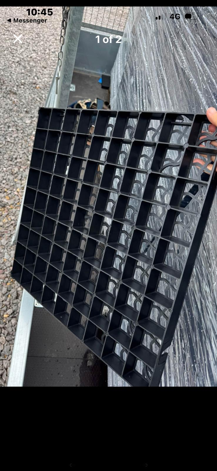 Black plastic gravel grid panel held above stacked materials